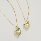 Two gold heart-shaped pendants on a light gray background