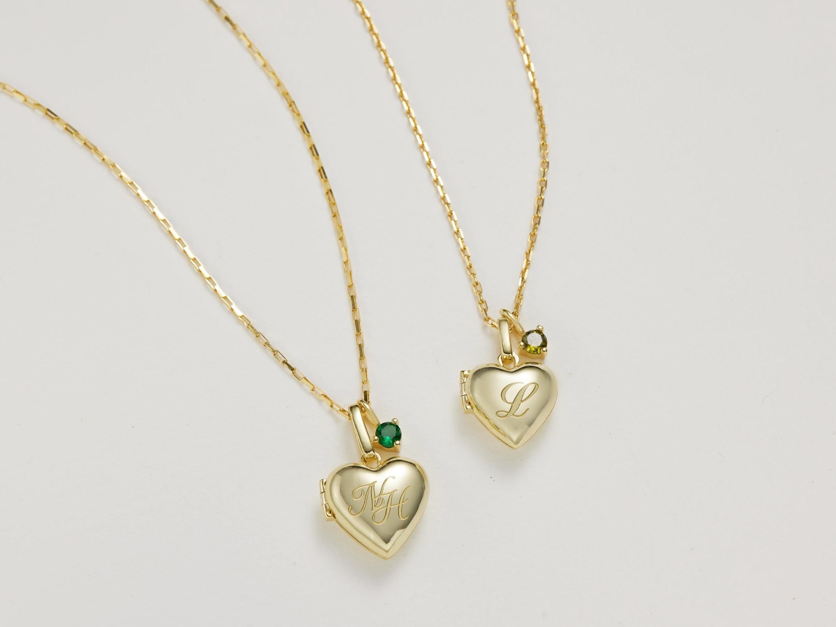 Two gold heart-shaped pendants on a light gray background