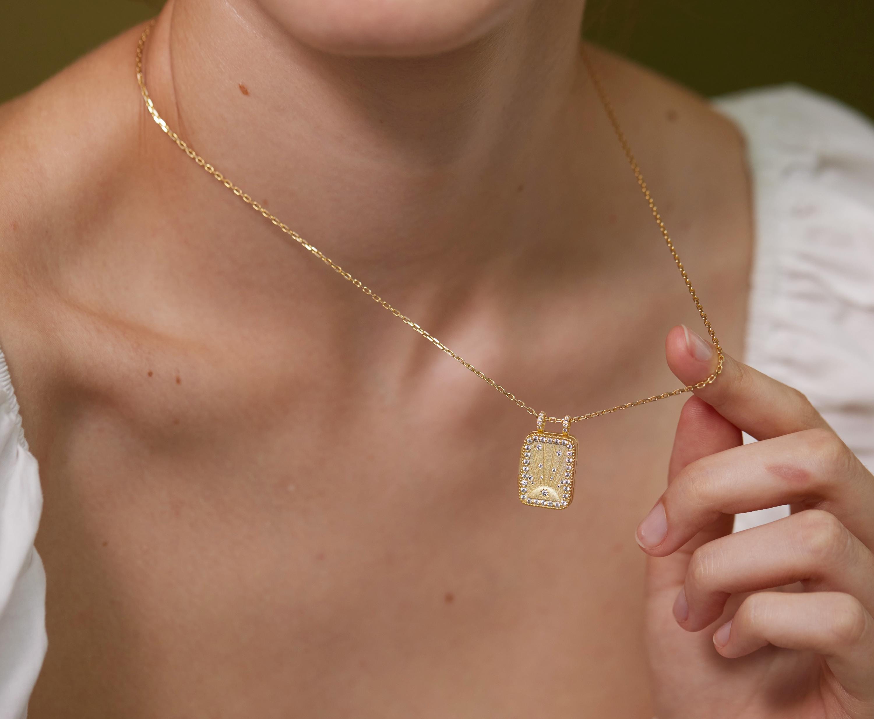 A close-up of a person's neck and chest wearing a gold necklace with a pendant.