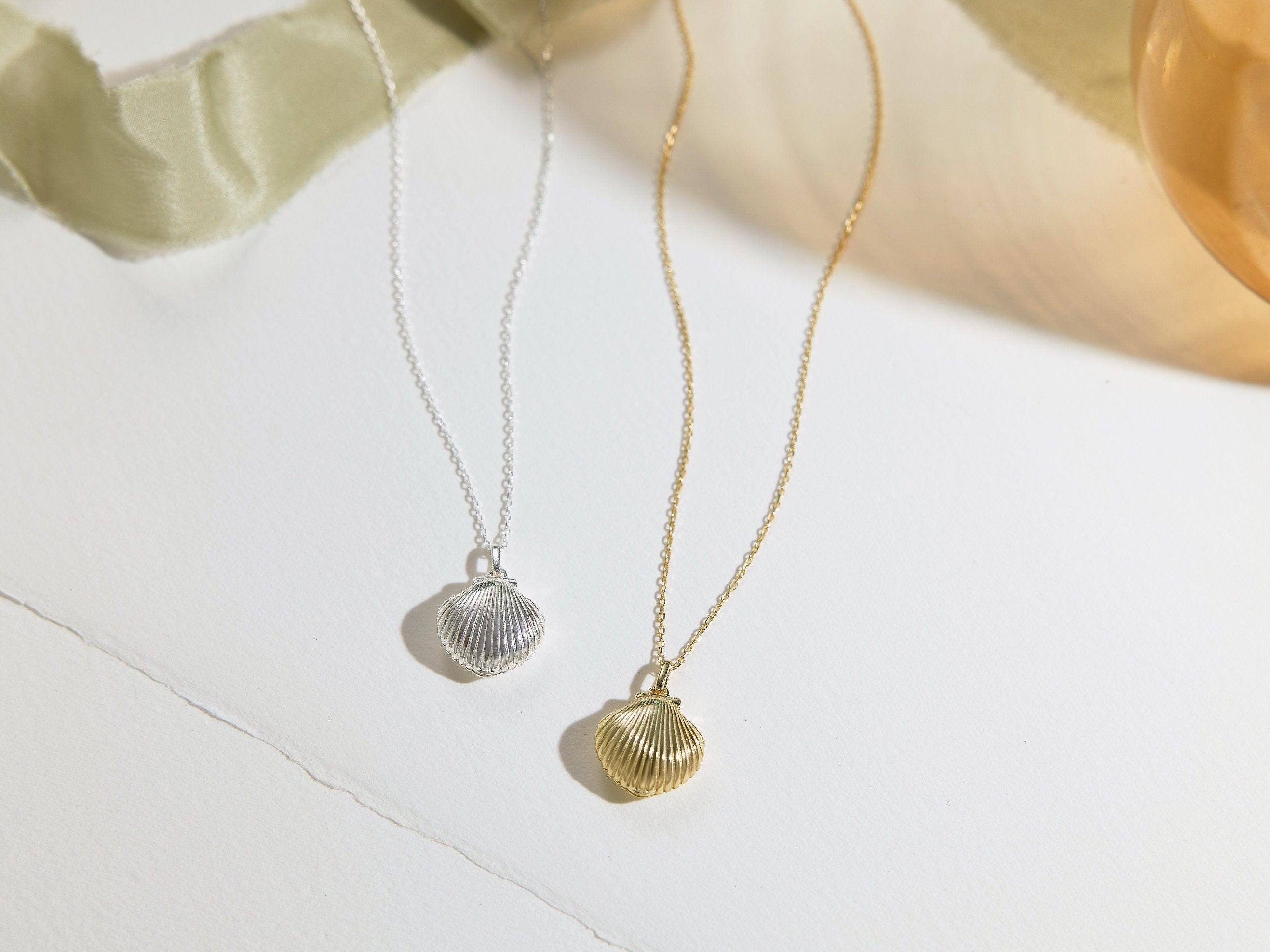 Two necklaces with shell pendants on a light background