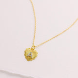 A delicate gold heart-shaped pendant necklace with a small gemstone is displayed against a plain white background.