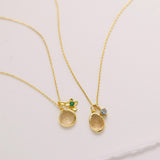 Two gold necklaces with pendants are displayed on a white surface.