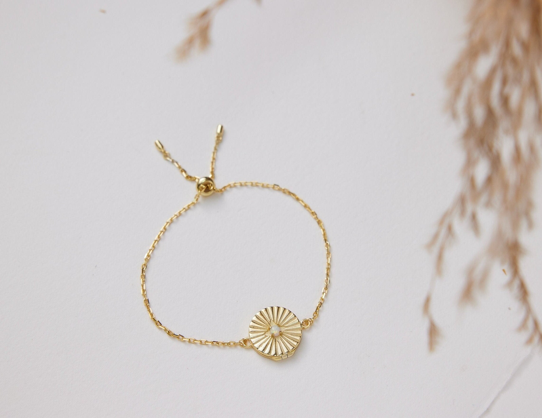 Gold bracelet with a sunflower charm on a light background