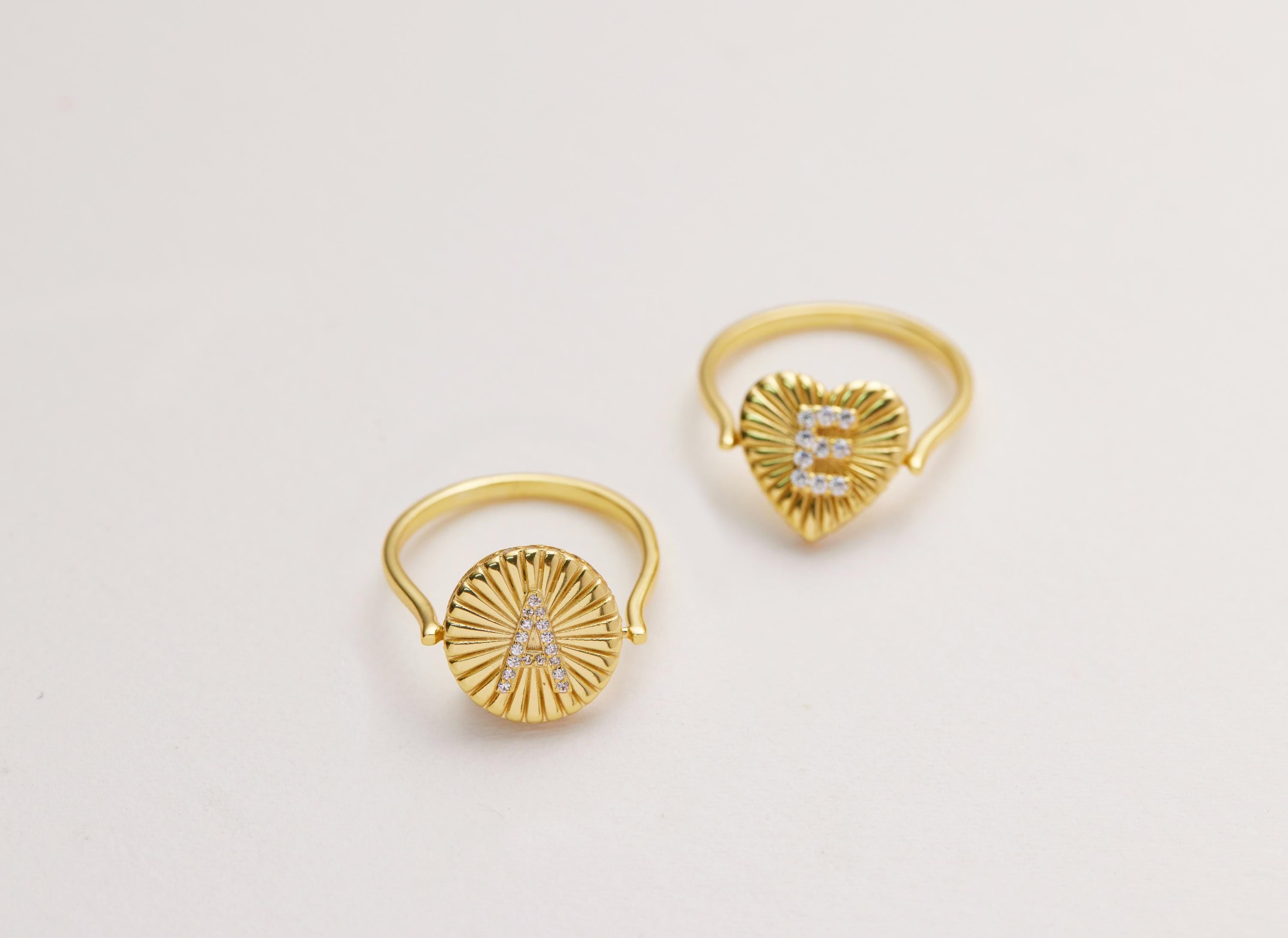 Two gold rings with personalized initial designs on them.