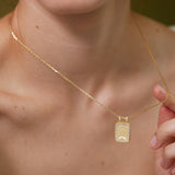 A close-up of a person's neck and chest wearing a gold necklace with a pendant.
