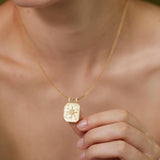 A close-up of a person's neck and chest area wearing a gold necklace with a pendant.