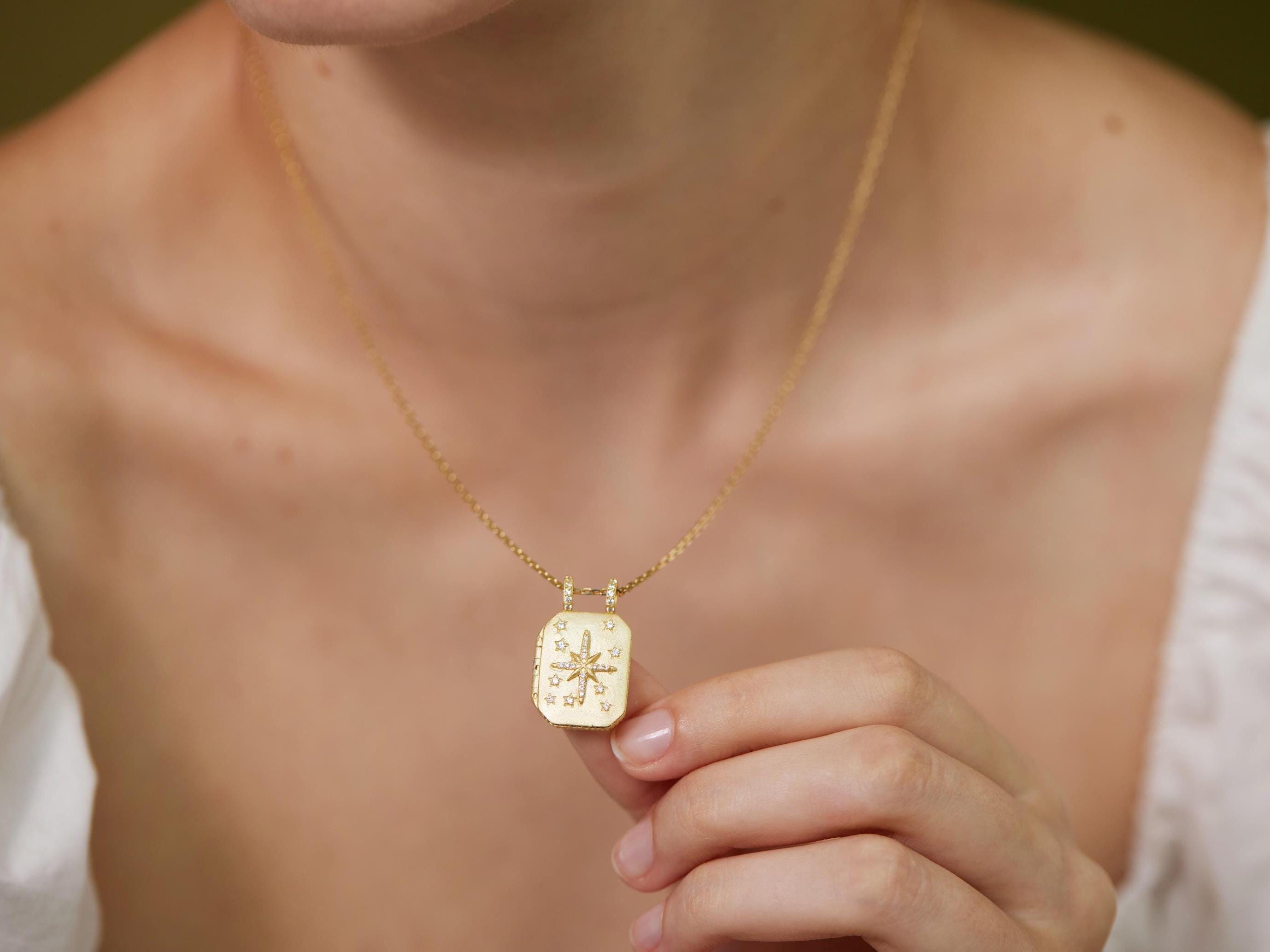 A close-up of a person&#39;s neck and chest area wearing a gold necklace with a pendant.