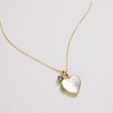 Gold necklace with a heart-shaped pendant on a light gray background