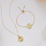 Gold necklace and bracelet set on a white surface