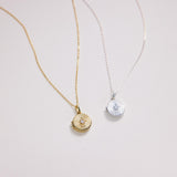 Two necklaces with circular pendants on a light gray background