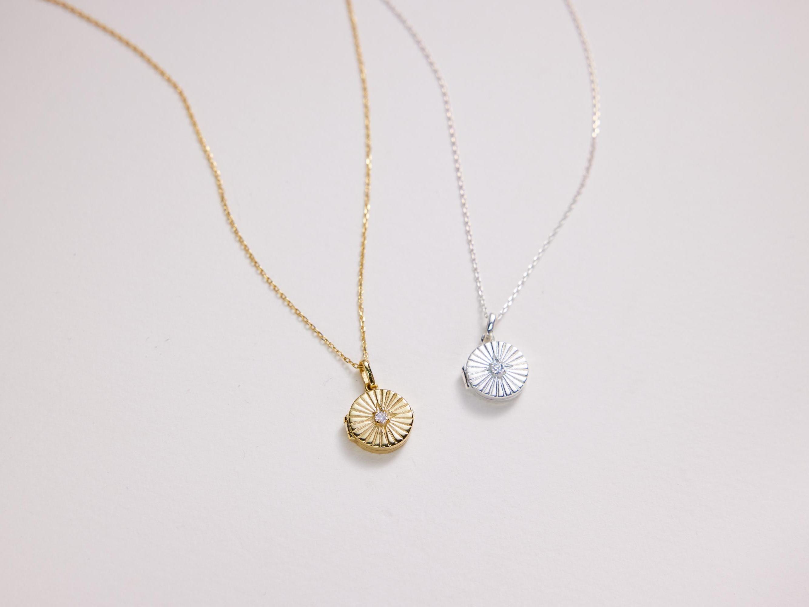 Two necklaces with circular pendants on a light gray background