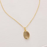 Gold necklace with a pendant on a light gray background