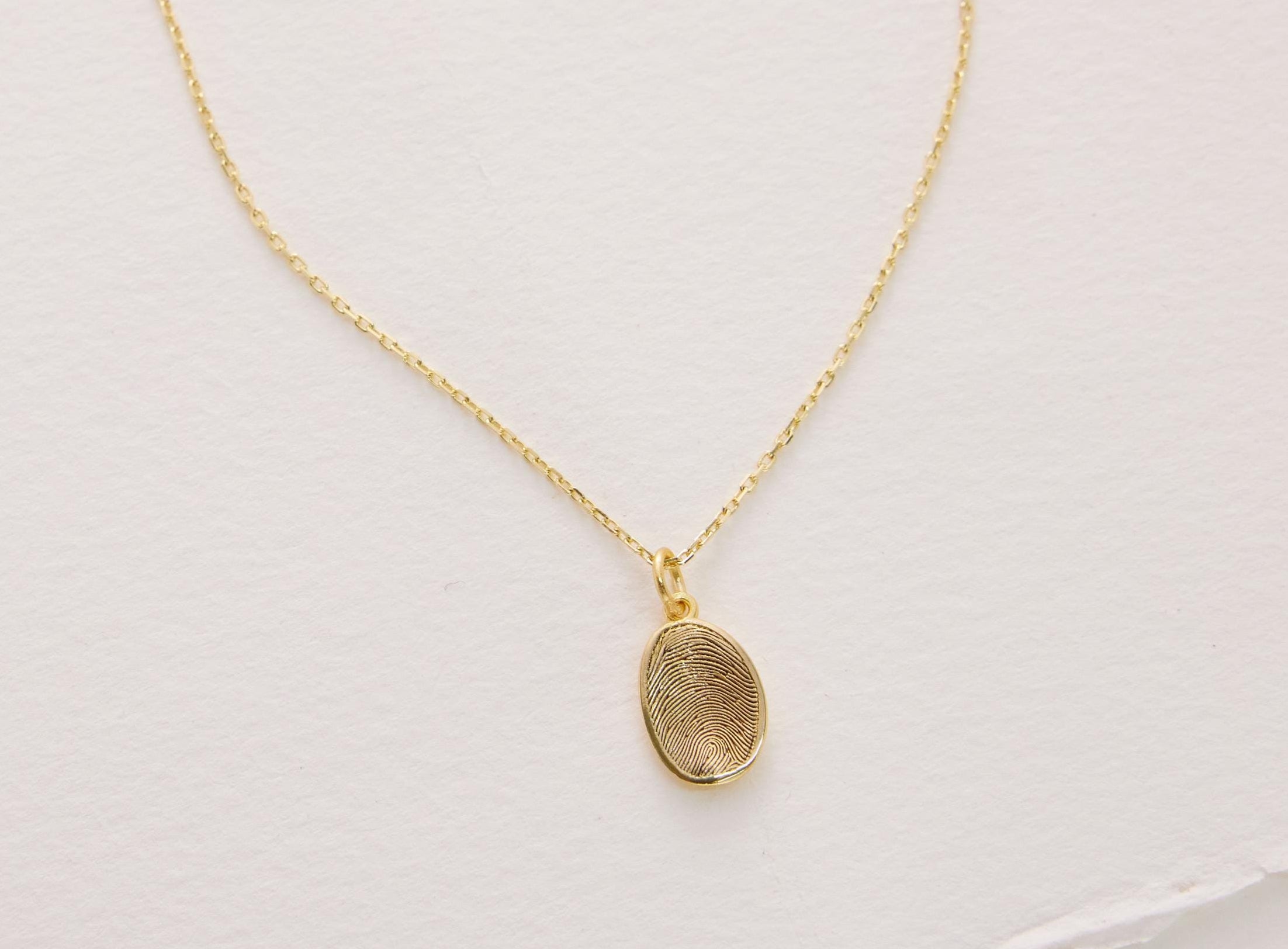 Gold necklace with a pendant on a light gray background